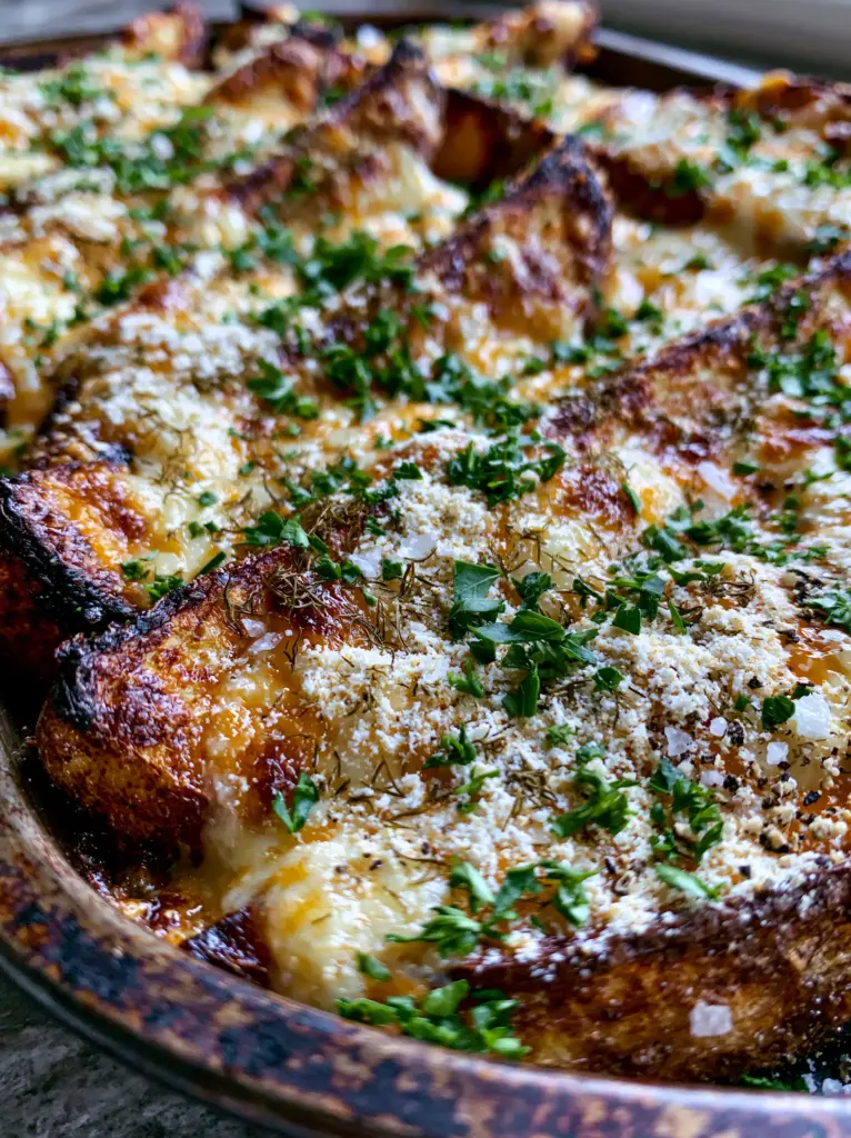 Macro shot of cheesy ranch potatoes showing charred russet edges and bubbling melted cheese.