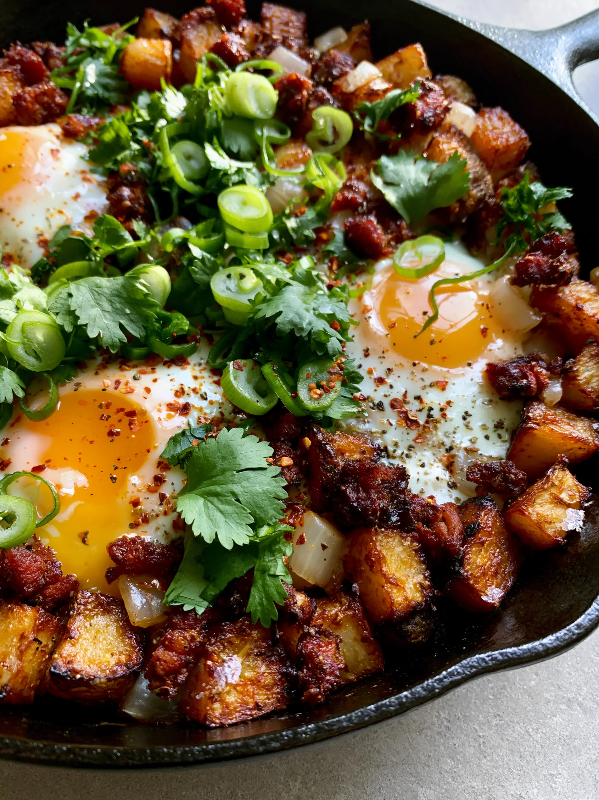 Breakfast Skillet Recipe with Crispy Potatoes and Spicy Chorizo 3 Close-up of crispy cubed potatoes and runny egg yolks in a breakfast skillet recipe.