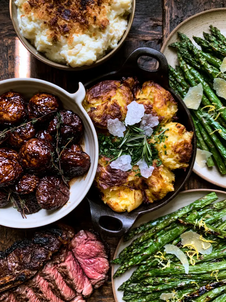 Side Dishes for Steak: The Ultimate Gourmet Steakhouse Spread 1 A medium-rare ribeye steak served with charred asparagus and creamy mac and cheese side dishes for steak.
