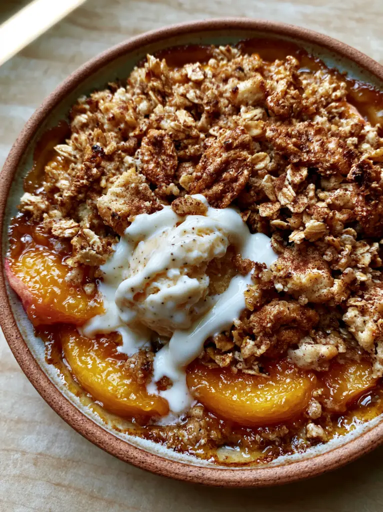 Top-down view of Peach Crisp showing vibrant orange-gold peaches and thick white rivers of melting ice cream.