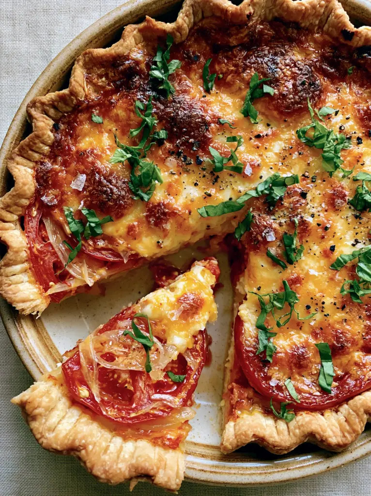 Southern Tomato Pie Recipe: The Ultimate Guide to a Crispy, Flaky Heirloom Classic 1 A slice of Southern Tomato Pie being lifted to show the crisp dry bottom crust and bubbling cheese peaks.
