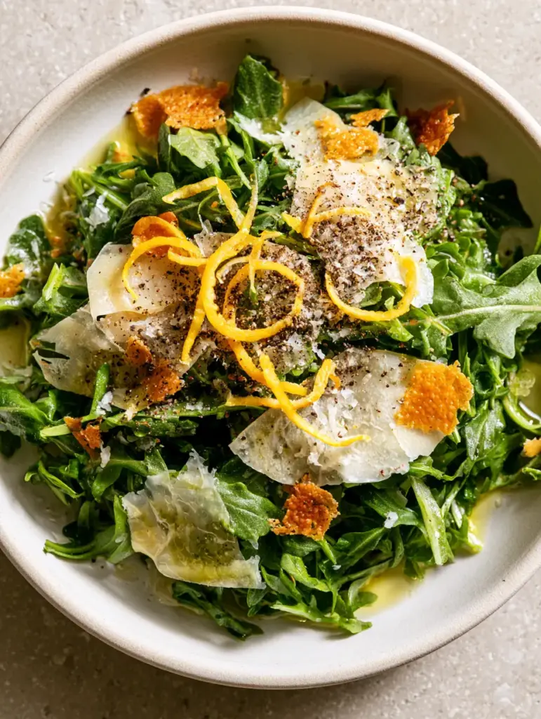 High-quality smartphone photo of Lemon Parmesan Salad showing bright yellow lemon curls and coarse black pepper.
