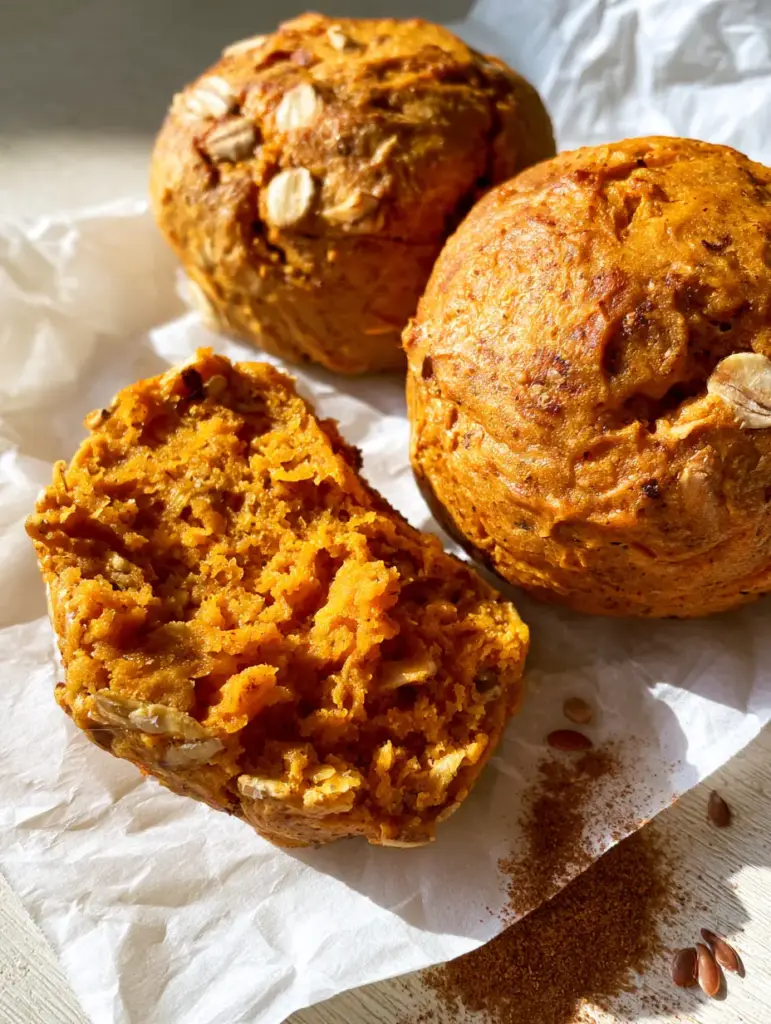 One Sweet Potato Breakfast Cookie broken in half, revealing a moist, vibrant orange interior and visible oats.