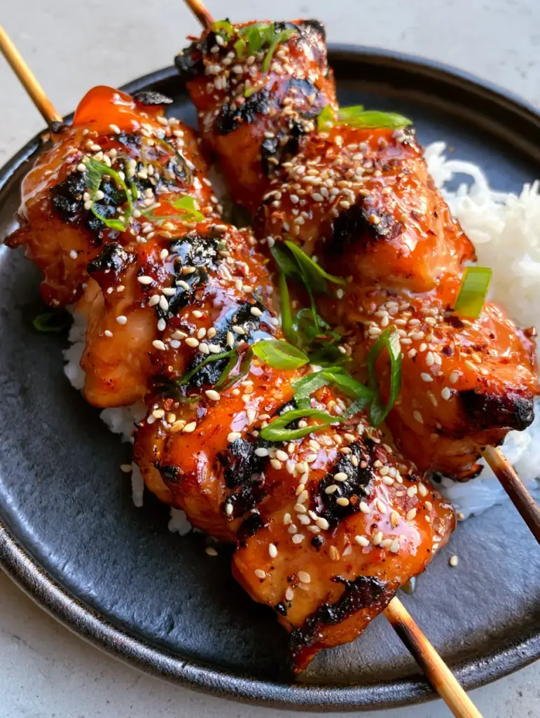 Sweet chili grilled chicken with Sticky Thai Glaze 2 Extreme close-up of Sweet chili grilled chicken chunks showing bubbly, reflective orange-red glaze and blackened grill marks.