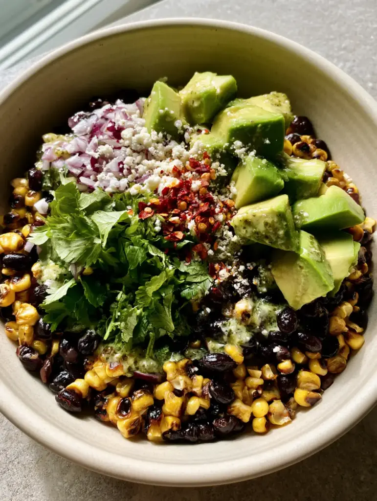 Corn Black Bean Avocado Salad with Fire-Charred Corn and Lime Crema 2 A vibrant top-down macro shot of a corn black bean avocado salad featuring fire-charred golden corn, glossy black beans, and buttery avocado.