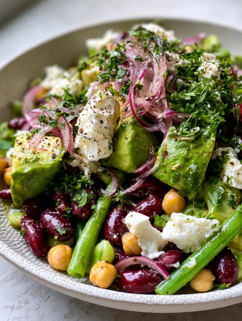 Macro view of Three-bean diabetic-friendly salad topped with large crumbles of white feta and fresh parsley.