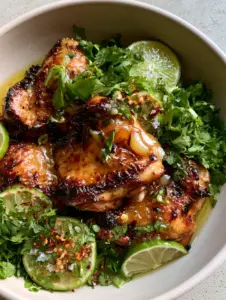 Close up shot of charred chicken skin with thick honey-lime glaze and red pepper flakes. (honey lime chicken recipe)