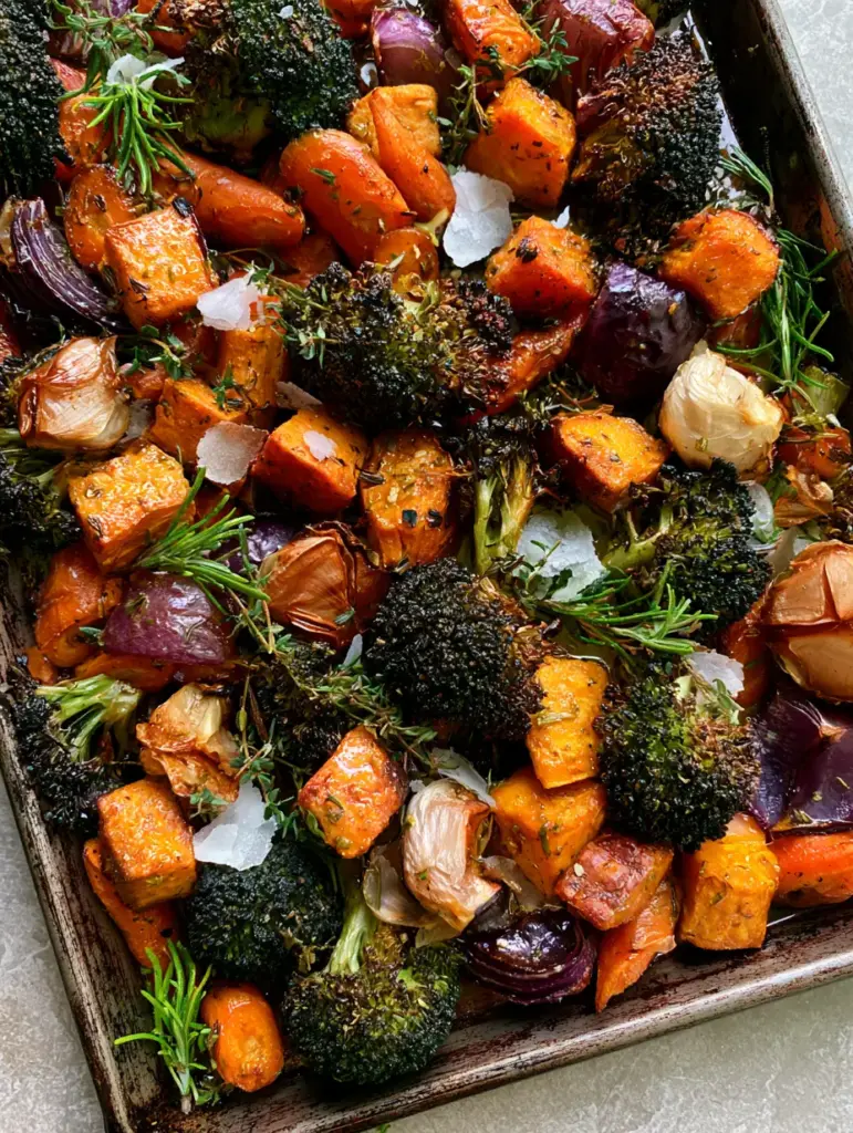 Close up shot of glistening garlic roasted vegetables with fresh herbs and large sea salt flakes.