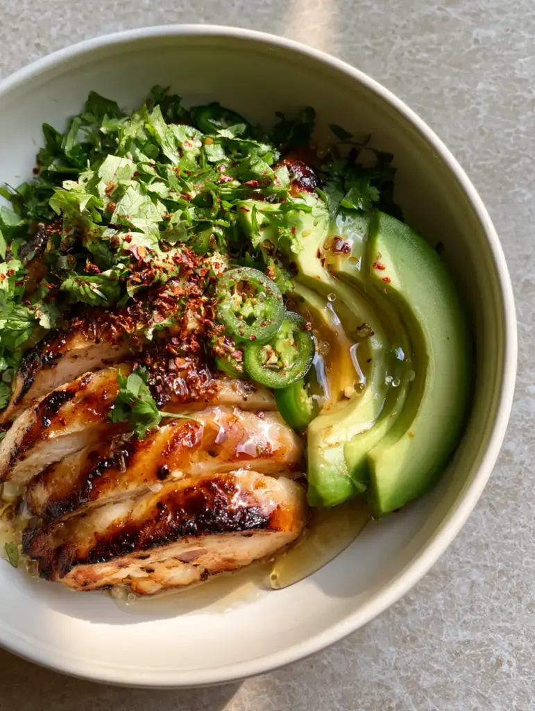 Honey Lime Chicken Avocado: The Ultimate 20-Minute Pan-Seared Dinner 1 Side view of honey lime chicken avocado bowl on a light-grey stone surface.