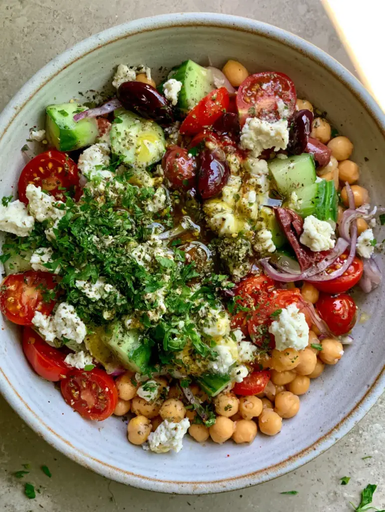 Top-down view of a Vegan summer salad featuring glossy olives, sliced red onion, and fresh parsley garnish.
